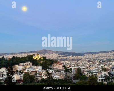 Vue du lever du soleil depuis la colline d'Areopagus avec le paysage urbain d'Athènes, mettant en valeur le bâtiment jaune et la montagne lointaine. Banque D'Images