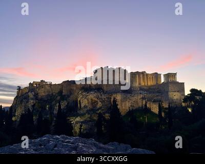 Lever de soleil sur la colline d'Areopagus avec la lumière chaude du matin illuminant l'Acropole et le paysage urbain d'Athènes. Banque D'Images
