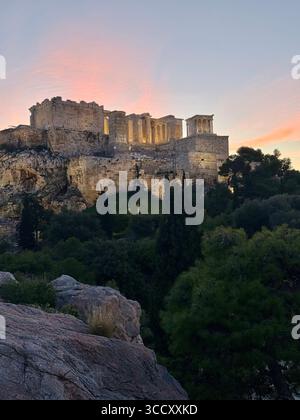 Lever de soleil sur la colline d'Areopagus avec la lumière chaude du matin illuminant l'Acropole et le paysage urbain d'Athènes. Banque D'Images