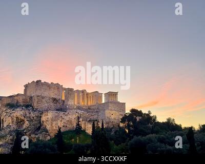 Lever de soleil sur la colline d'Areopagus avec la lumière chaude du matin illuminant l'Acropole et le paysage urbain d'Athènes. Banque D'Images