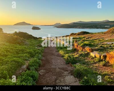 La lumière de l'heure d'or baigne le site archéologique de Sounion, en Grèce, y compris les sentiers et les ruines près du temple de Poséidon. Banque D'Images