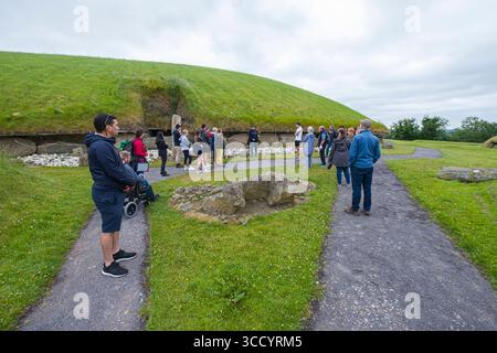 Groupe de touristes écoutant le guide local parler du site 1 de Knowth, d'une tombe de passage néolithique et d'un monument antique à Brú na Bóinne, patrimoine mondial Banque D'Images