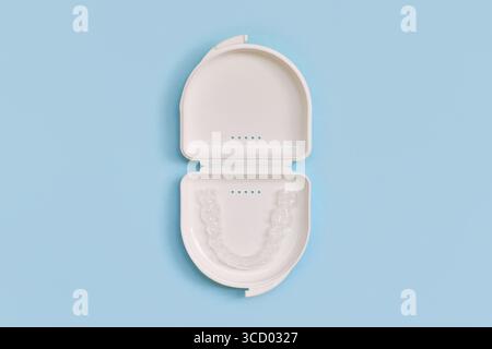 Protège-dents dentaires transparents personnalisés aligners clairs pour la mâchoire inférieure dans un boîtier blanc sur fond bleu Banque D'Images