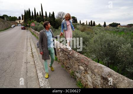 Père soutient sa fille alors qu'elle marche soigneusement le long d'un ancien mur de pierre au bord de la route. Ils profitent d'une promenade paisible à travers la campagne, s Banque D'Images