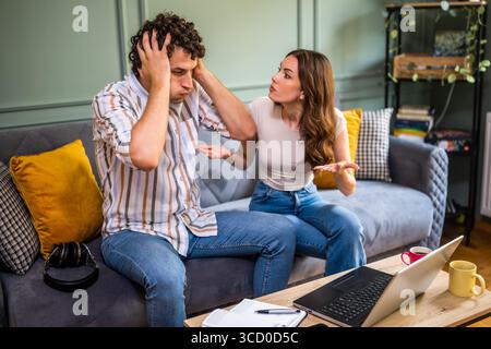 La femme est en colère parce que son homme travaille trop. Freelance travaillant à domicile et discutant avec sa femme. Banque D'Images