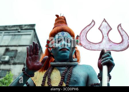 Narayanganj, Bangladesh - 23 août 2019 : vue d'un artiste représentant Shiva avec une peau bleue frappante et une perruque orange vibrante, tenant un trident symbolique. Banque D'Images