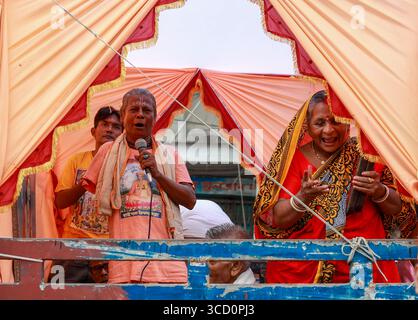 Narayanganj, Bangladesh - 23 août 2019 : vue de dévots chantant et priant dans des vêtements orange et rouge vifs, encadrés par une tente, lors d'une procession. Banque D'Images