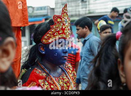 Narayanganj, Bangladesh - 23 août 2019 : vue d'une personne à la peau bleue frappante et aux vêtements rouges et dorés vifs au milieu des rues animées. Banque D'Images