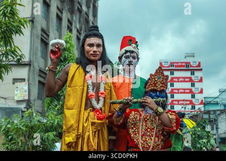 Narayanganj, Bangladesh - 23 août 2019 : vue d'artistes en costumes vifs, leurs visages peints de couleurs saisissantes, debout sur fond de bâtiments urbains. Banque D'Images