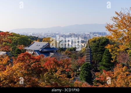 Le feuillage lumineux d'automne entoure une pagode en pierre et des bâtiments traditionnels dans le parc du temple de Kiyomizu-dera, Kyoto, Japon, avec une vue large sur l'ic Banque D'Images