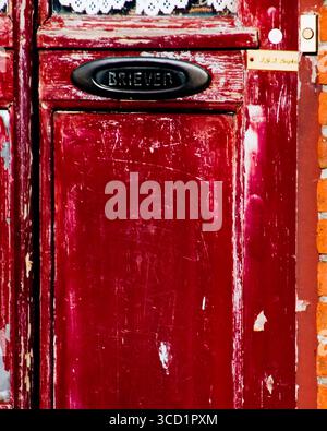 Gros plan d'une porte rouge avec un slot « BRIEVER » et une plaque signalétique portant la mention « J.G.J. Siepke ». Banque D'Images