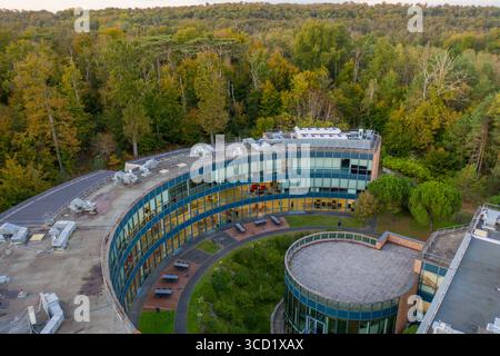 Fontainebleau, France - 22 octobre 2024 : vue aérienne du bâtiment courbé de l'INSEAD Business School niché au milieu d'une forêt dynamique, mélange d'architecture moderne et de teintes automnales. Banque D'Images