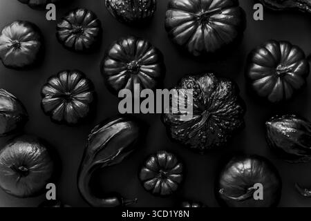 Différents types de petits citrouilles peintes en noir sur fond sombre. Vue de dessus, plan d'agencement Banque D'Images