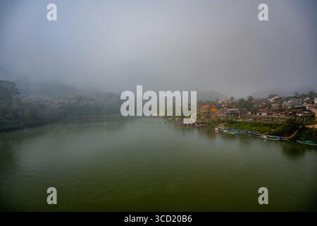 Matinée brumeuse sur Riverside Village et bateaux le long de la rivière Nam ou dans le district de Ngoy, au nord du Laos Banque D'Images