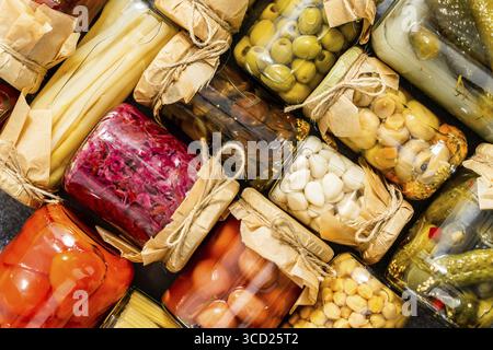 Divers types de conserves de légumes et de champignons dans des pots en verre. Vue de dessus, plan d'agencement Banque D'Images