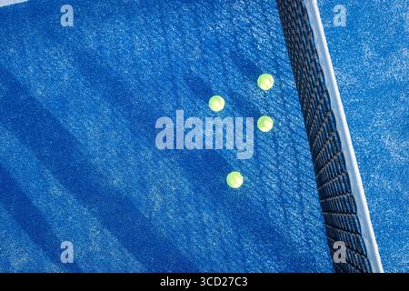Court de padel bleu avec de longues ombres rayées et des balles, vue de dessus. Banque D'Images