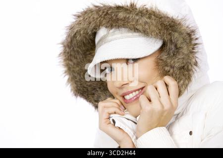 Jolie femme avec un joli sourire chaleureux et amical à la mode hivernale portant un haut à capuche garni de fourrure Banque D'Images