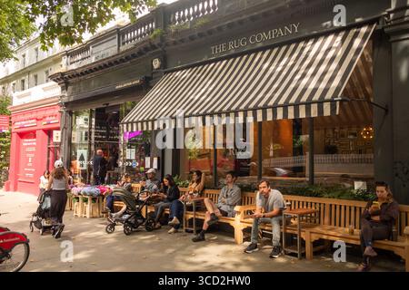 LONDRES - 28 JUILLET 2025 : des gens assis à boire un café sur Holland Park Avenue à Notting Hill, dans le centre-ouest de Londres Banque D'Images