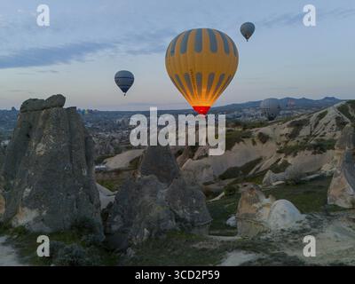 Montgolfières planant au-dessus d'un paysage rocheux à l'aube en Cappadoce, vue aérienne, parc national de Goereme, Goereme Tarihi Milli Parki, Nevsehir Pro Banque D'Images
