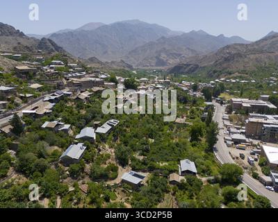Vue panoramique d'un village le long d'une route au milieu de collines verdoyantes et de montagnes, vue aérienne, Meghri, province de Syunik, les montagnes en arrière-plan sont locat Banque D'Images