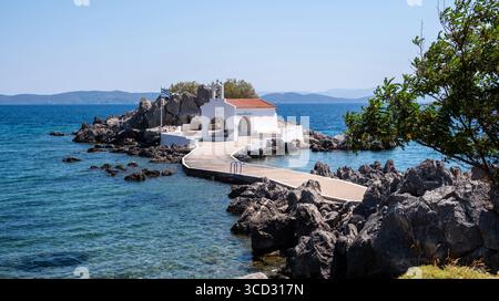 Chios, petite église d'Agios Isidoros, Grèce. Chapelle d'architecture traditionnelle avec toit de tuiles rouges et clocher sur les rochers, journée d'été ensoleillée Banque D'Images