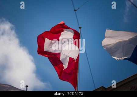 Drapeau suisse agitant au vent. Vue en bas angle, gros plan, journée d'été ensoleillée, regarder vers le haut, téléobjectif, personne Banque D'Images