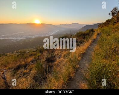 Beau coucher de soleil sur la vallée du Var et les montagnes depuis un sentier de randonnée dans les collines au-dessus de Nice, Côte d'Azur. Banque D'Images
