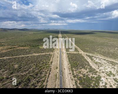 Vue aérienne du paysage désertique aride avec route sinueuse et collines lointaines sous un vaste ciel, Vingerklip, Kunene, Namibie. Banque D'Images