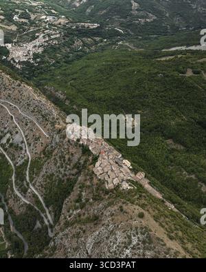 Vue aérienne de l'ancien village accroché à la crête de la montagne, entouré de forêts verdoyantes et de routes sinueuses, Castrovalva, Abruzzes, Italie. Banque D'Images