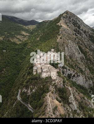Vue aérienne de l'ancien village accroché à une crête précipitée, encadrée par des montagnes escarpées et des vallées verdoyantes sous un ciel couvant, Castrovalva, Abruzzes, Italie. Banque D'Images