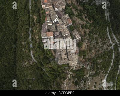 Vue aérienne de bâtiments anciens groupés avec des toits en terre cuite accrochés au paysage rocheux escarpé, niché au milieu de forêts verdoyantes, Castrovalva, Banque D'Images