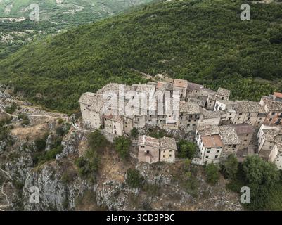Vue aérienne de l'ancien village accroché à l'affleurement rocheux, une tapisserie de toits en terre cuite contre la colline verdoyante, Castrovalva, Abruzzes, Italie. Banque D'Images