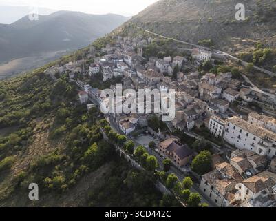 Vue aérienne de l'ancien village accroché à la montagne, ses bâtiments en pierre et ses toits en terre cuite se mélangeant parfaitement avec le paysage accidenté, Rocca Calascio, Abruzzes, Italie. Banque D'Images