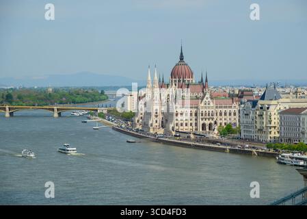 L'impressionnant bâtiment du Parlement hongrois se dresse au bord du Danube à Budapest, mettant en valeur sa beauté architecturale sous un ciel bleu clair. Bateaux Banque D'Images