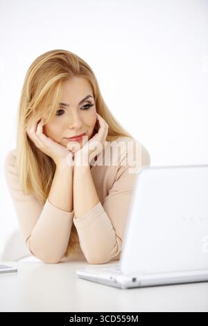 Jolie jeune femme blonde regardant inquiet à son ordinateur portable Banque D'Images