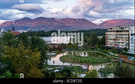 Vue panoramique sur un parc avec un étang, des arbres et des montagnes en arrière-plan. Banque D'Images