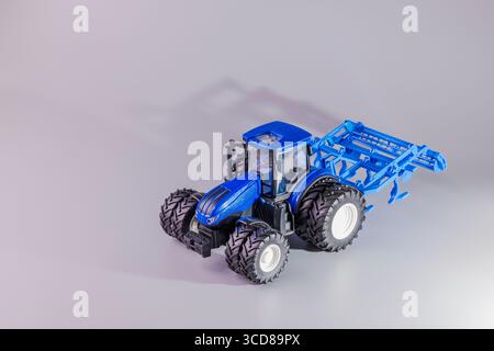 Vue rapprochée d'un tracteur RC bleu avec pneus larges et accessoire de charrue arrière pour le travail du sol. Suède. Banque D'Images