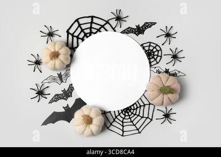 Composition d'Halloween de citrouilles tricotées grises et beiges, de toiles d'araignée noires et d'araignées et de chauves-souris avec un endroit blanc rond pour le texte. Jouets tricotés faits à la main pour enfants et décoration de maison de vacances. Banque D'Images