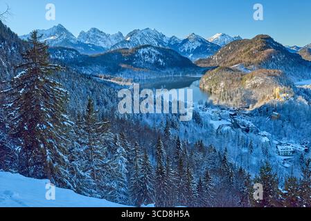 Une vue panoramique époustouflante capture l'essence d'une scène hivernale de conte de fées dans les Alpes bavaroises. Un château de renommée mondiale perche majestueusement au sommet d'un Snow-c Banque D'Images