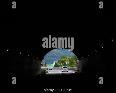 Extrémité du tunnel en demi-cercle. Voiture passant par le tunnel, voir clairement vue de face. Circulation légère en Italie rurale, sur le chemin de Dolomite. Banque D'Images