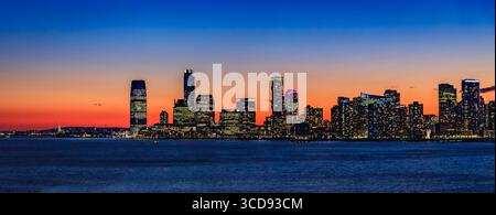 La silhouette de Jersey City vue de New York City avec un coucher de soleil spectaculaire et des nuages colorés sur le fleuve Hudson dans le New Jersey, États-Unis Banque D'Images