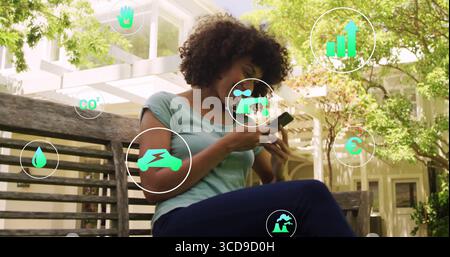 En utilisant un smartphone, femme interagissant sur un banc en bois sous pergola dans le jardin, avec des icônes éco numériques Banque D'Images