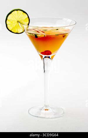 Cocktail rafraîchissant servi dans un verre à martini garni d'une rondelle de citron vert et d'une cerise, isolé sur fond blanc. Banque D'Images