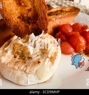 Dégustez un fromage camembert délicieusement cuit, parfaitement complété par des tomates grillées et des toasts croustillants Banque D'Images