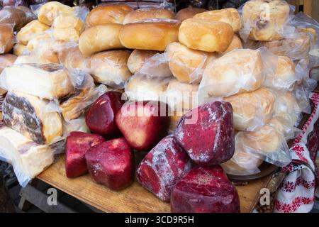 Assortiment coloré de fromages fumés et aromatisés avec charcuteries exposées au marché agricole. Variété de textures et de couleurs, parfait pour Cu Banque D'Images