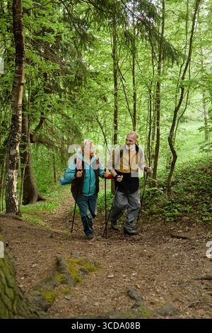 Couple caucasien senior randonnée ensemble dans la forêt et profiter de la promenade dans la nature Banque D'Images
