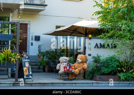 Deux ours en peluche doux assis à une table, boire Aperol dans la rue italienne café Ama 18 chambres hôtel à Côme. Italie, Côme - 17 juillet 2025. Banque D'Images