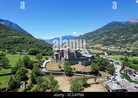 Vue aérienne de l'imposant château de Fénis debout fièrement au milieu de l'étreinte verdoyante de la vallée, un contraste frappant avec le ciel Azur au-dessus, Fénis, Aoste V. Banque D'Images