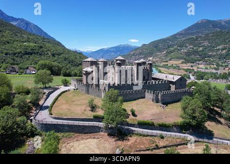 Vue aérienne du château médiéval de Fénis avec ses murs crénelés et ses tours, fièrement sur fond de verdoyant lan de la vallée d'Aoste Banque D'Images