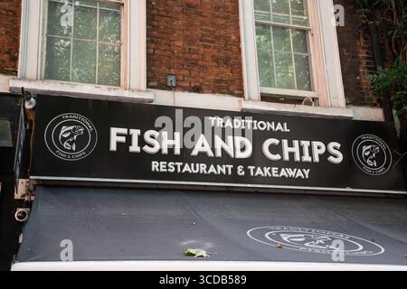 Boutique panneau indiquant « Traditional Fish and Chips – Restaurant and Takeaway », promouvant la cuisine britannique classique dans un cadre décontracté. Banque D'Images